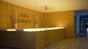 A reception desk with a wooden panel design and the name "LA ISLA HUATULCO" on the wall.