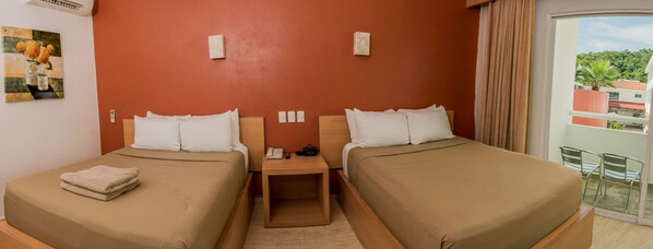 Habitación de hotel con dos camas, una mesita de noche con teléfono y radio, y un cuadro en la pared.