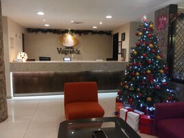 A hotel reception area with a Christmas tree, a reception desk, and a red chair.