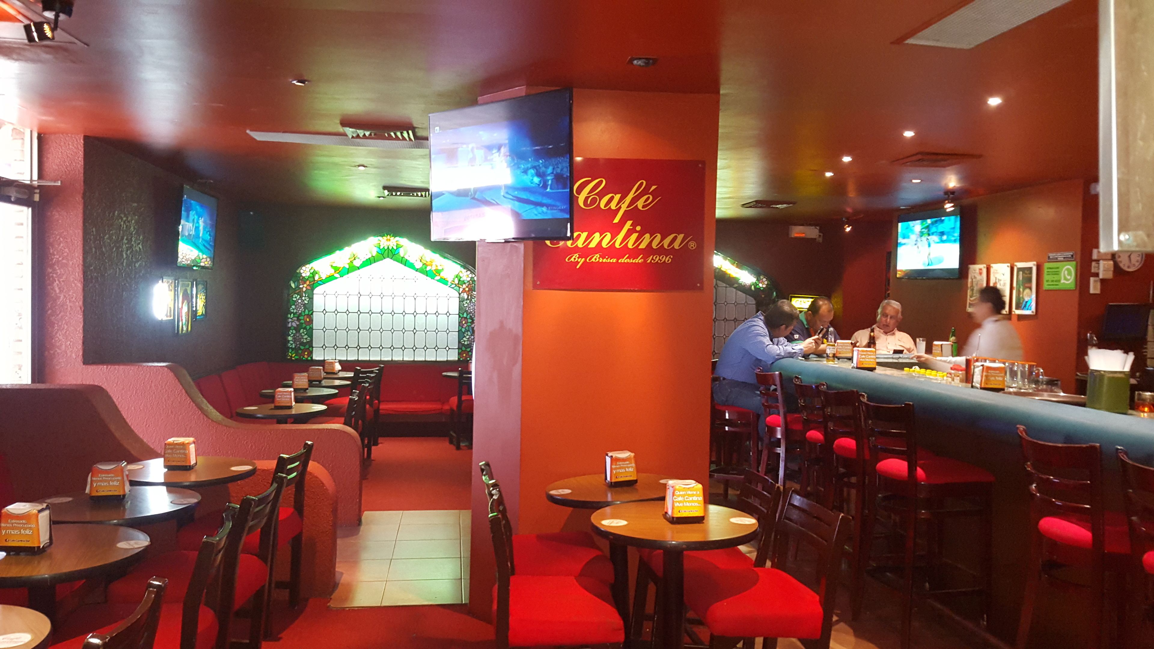 A restaurant interior with booths and tables, a bar area, and a TV screen displaying a program.