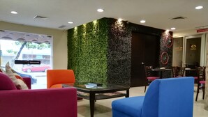 Um interior moderno com parede verde, mesa de vidro e assentos coloridos.