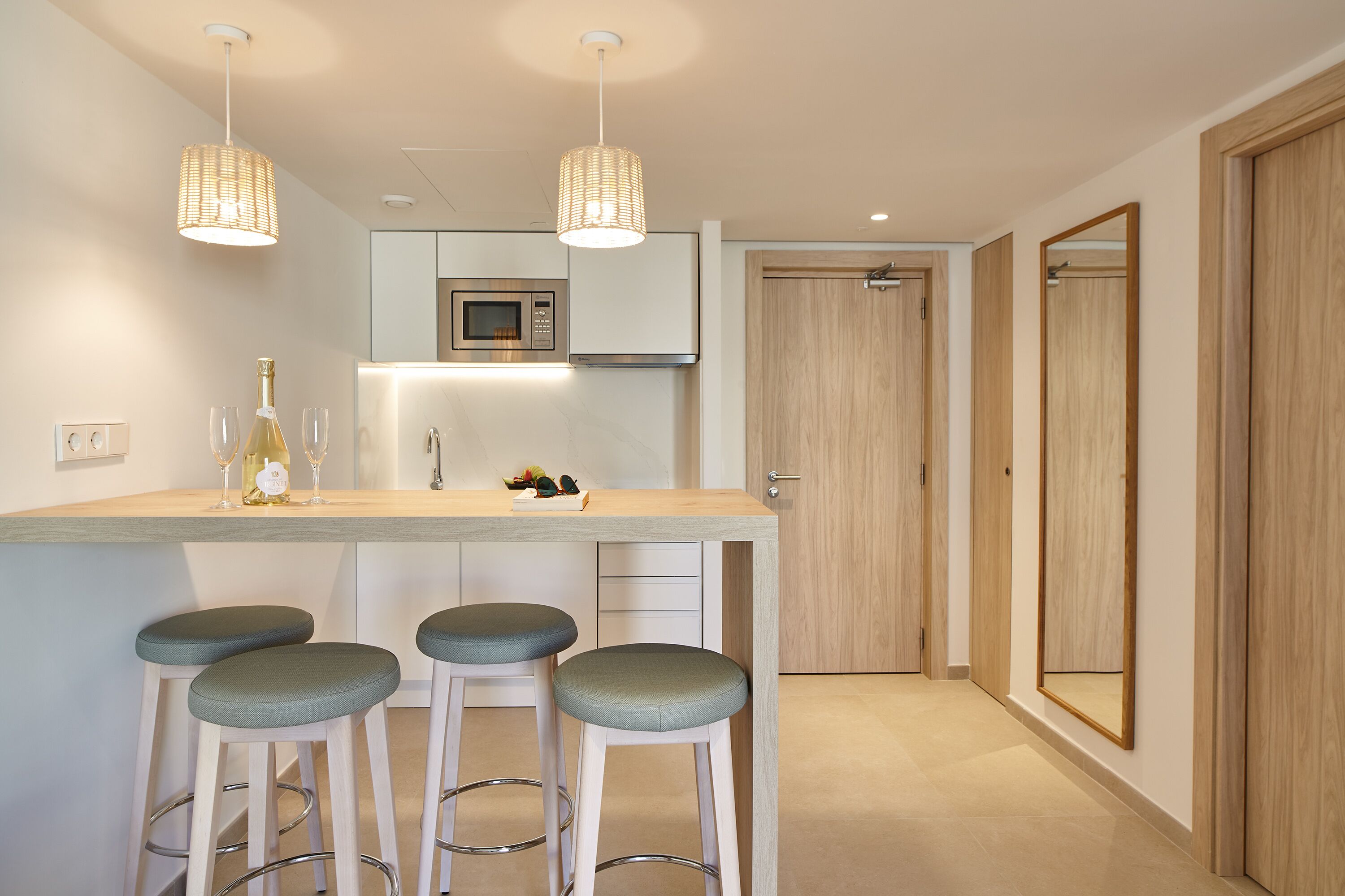 Une cuisine moderne dotée d’un îlot central, de tabourets de bar, d’un four à micro-ondes et de luminaires suspendus.