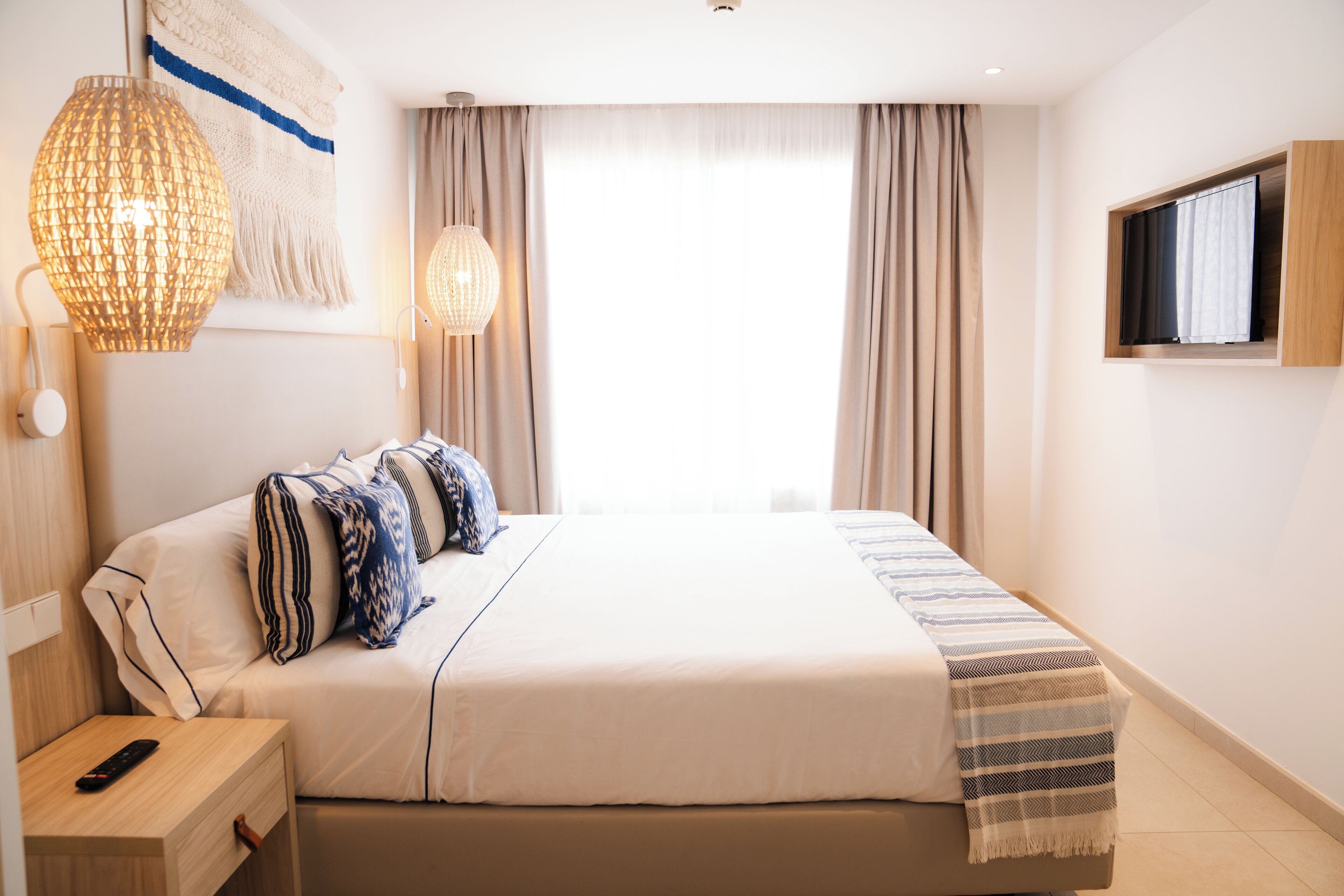 Una camera d'albergo ordinata con un letto grande, comodini e un televisore montato a parete.