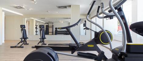 Ett gym med konditionsmaskiner, speglar och ett trägolv.