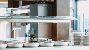 A modern kitchen with a wooden countertop, white plates, and potted plants. - Apartamentos El Palmar (San Bartolomé de Tirajana)