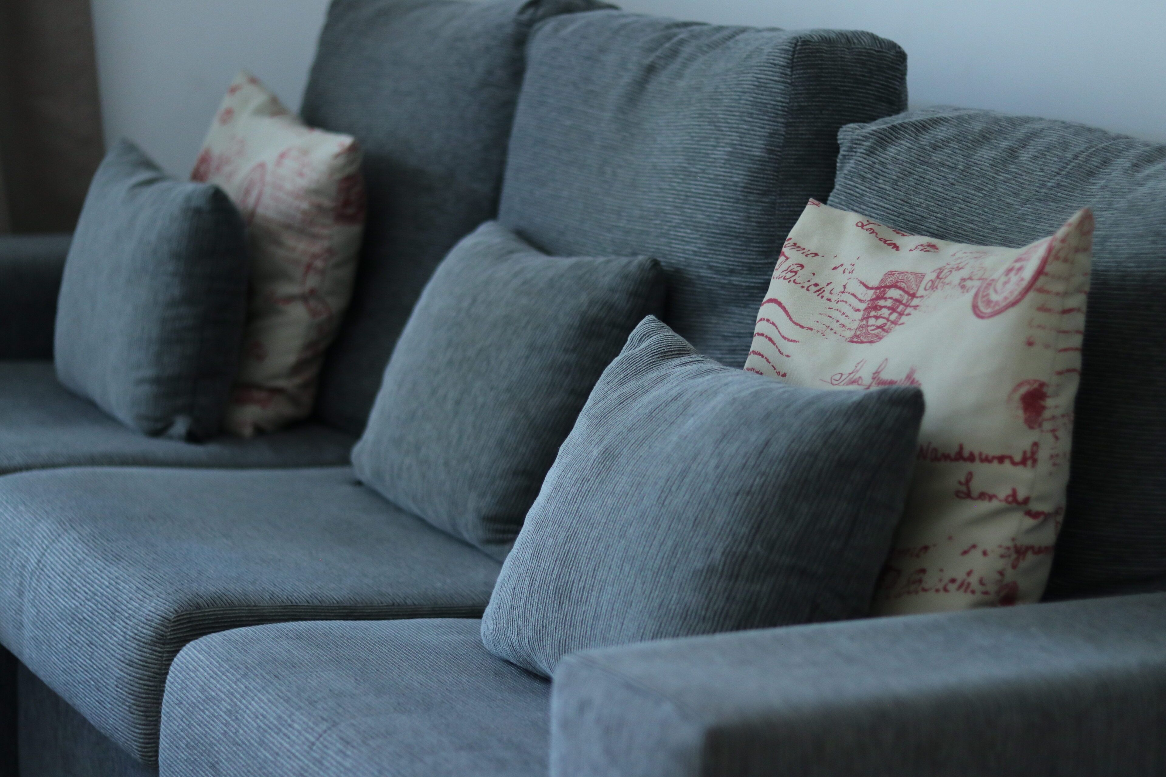 A grey sofa with multiple cushions, one with a vintage design.