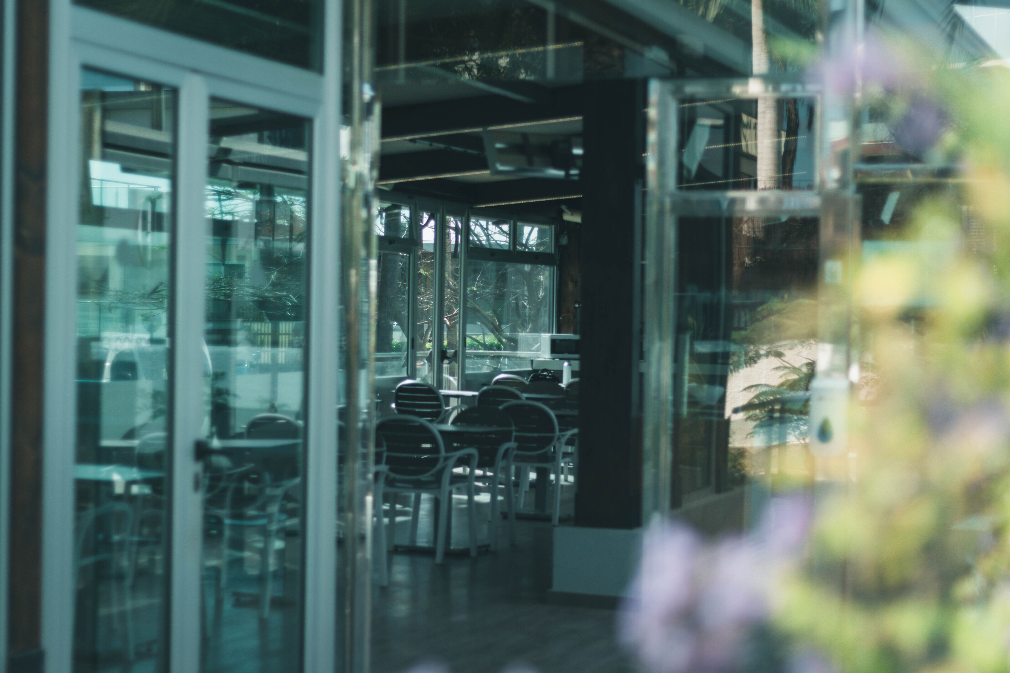 An indoor space with glass partitions, tables, and chairs arranged for dining or meetings.