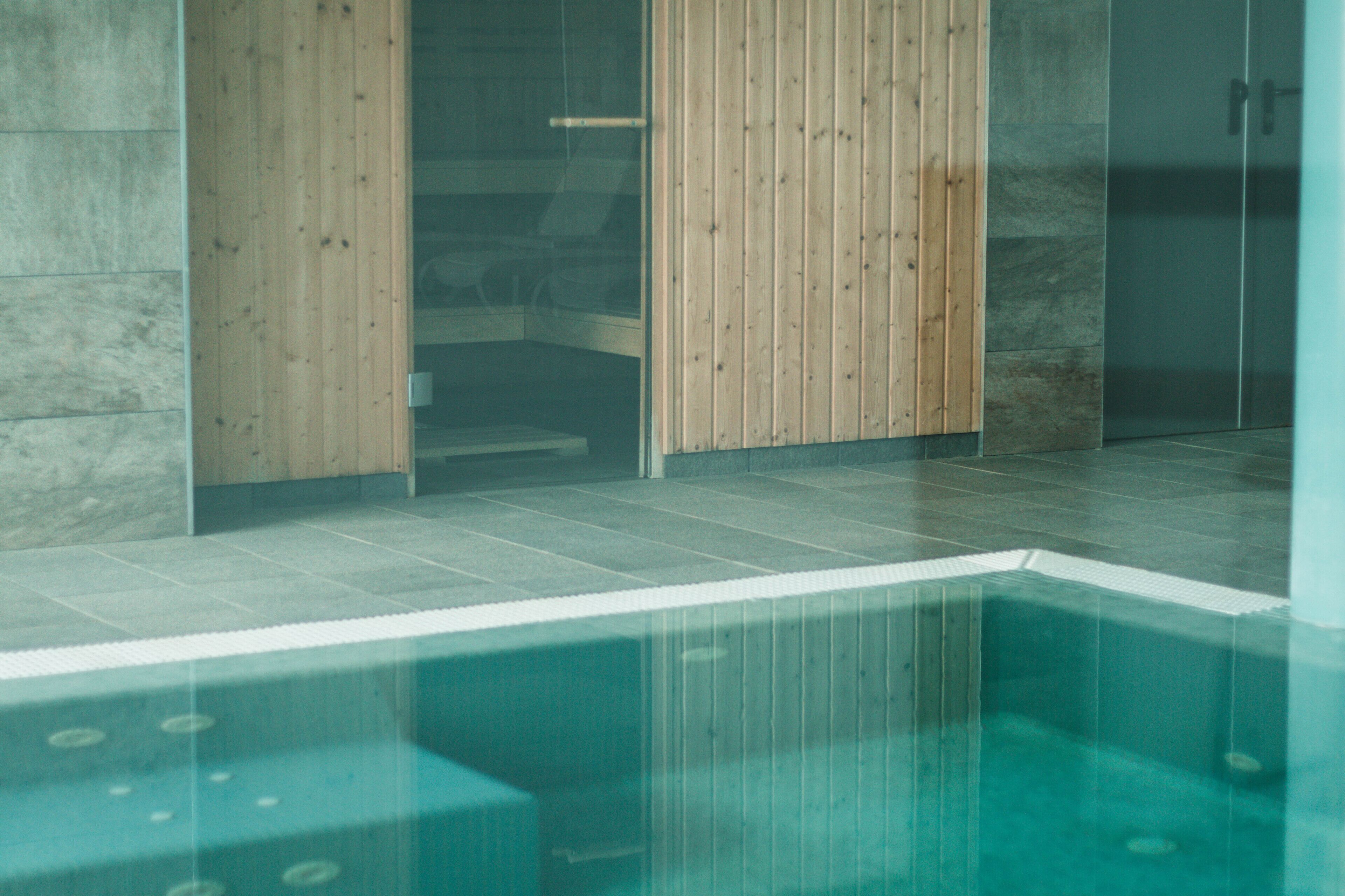 A modern indoor pool area with wooden paneling and tiled flooring.