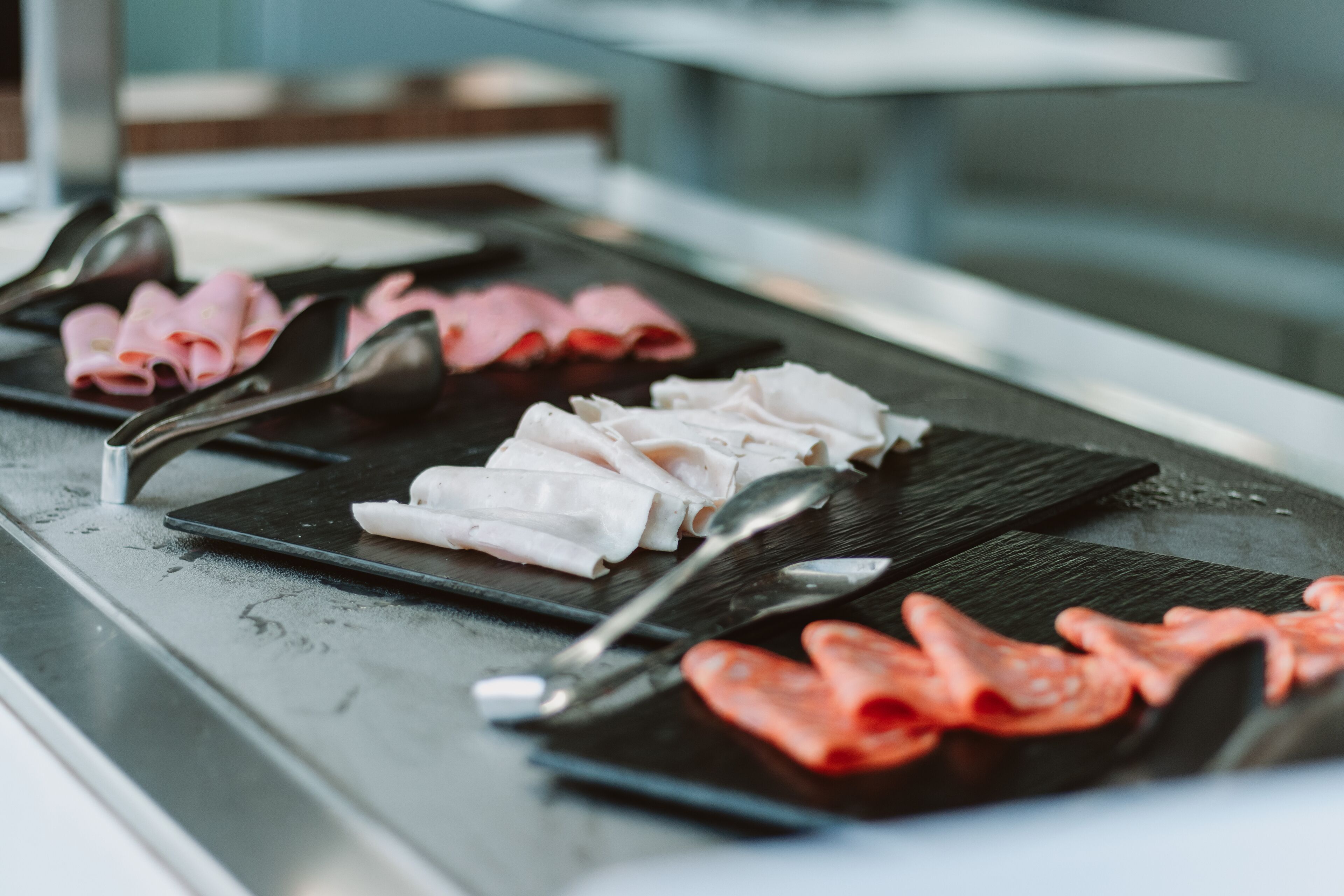 A buffet with various meats and utensils.