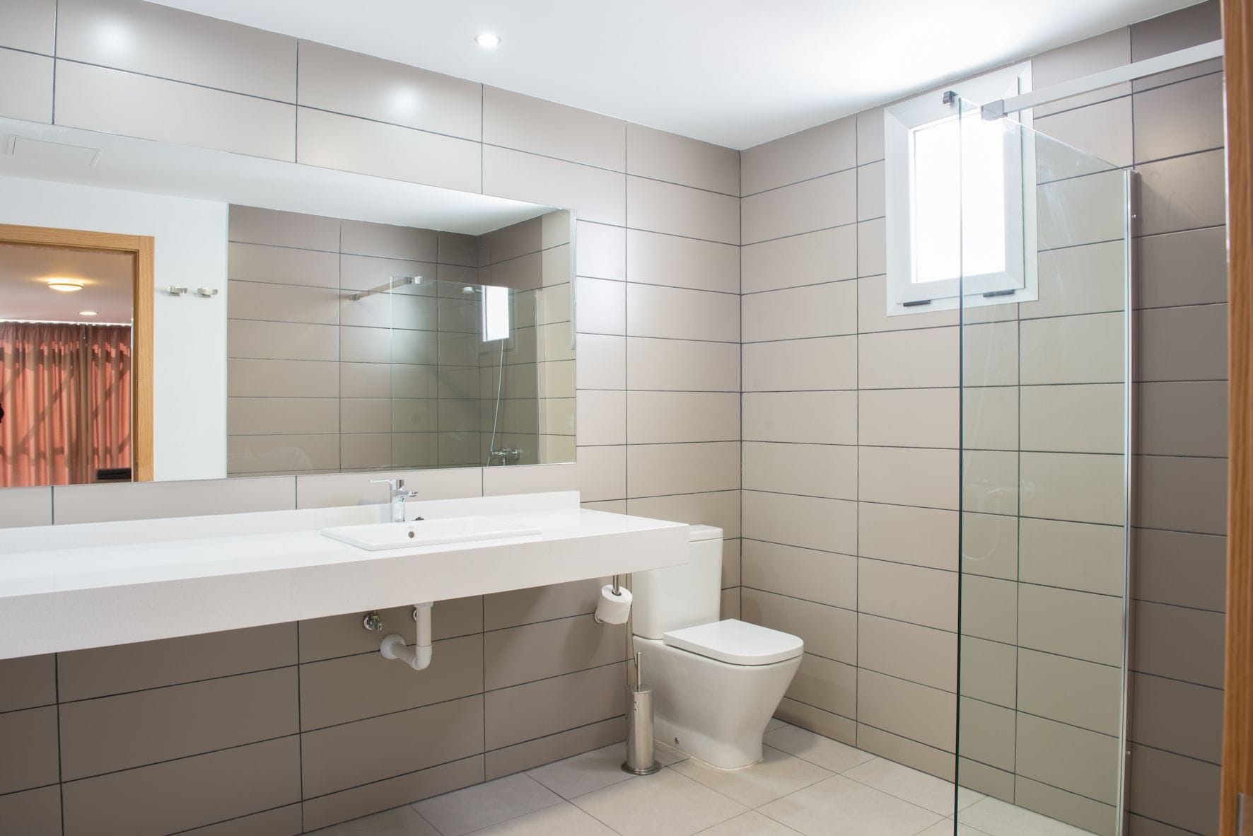 A modern bathroom with a white sink, mirror, and toilet.
