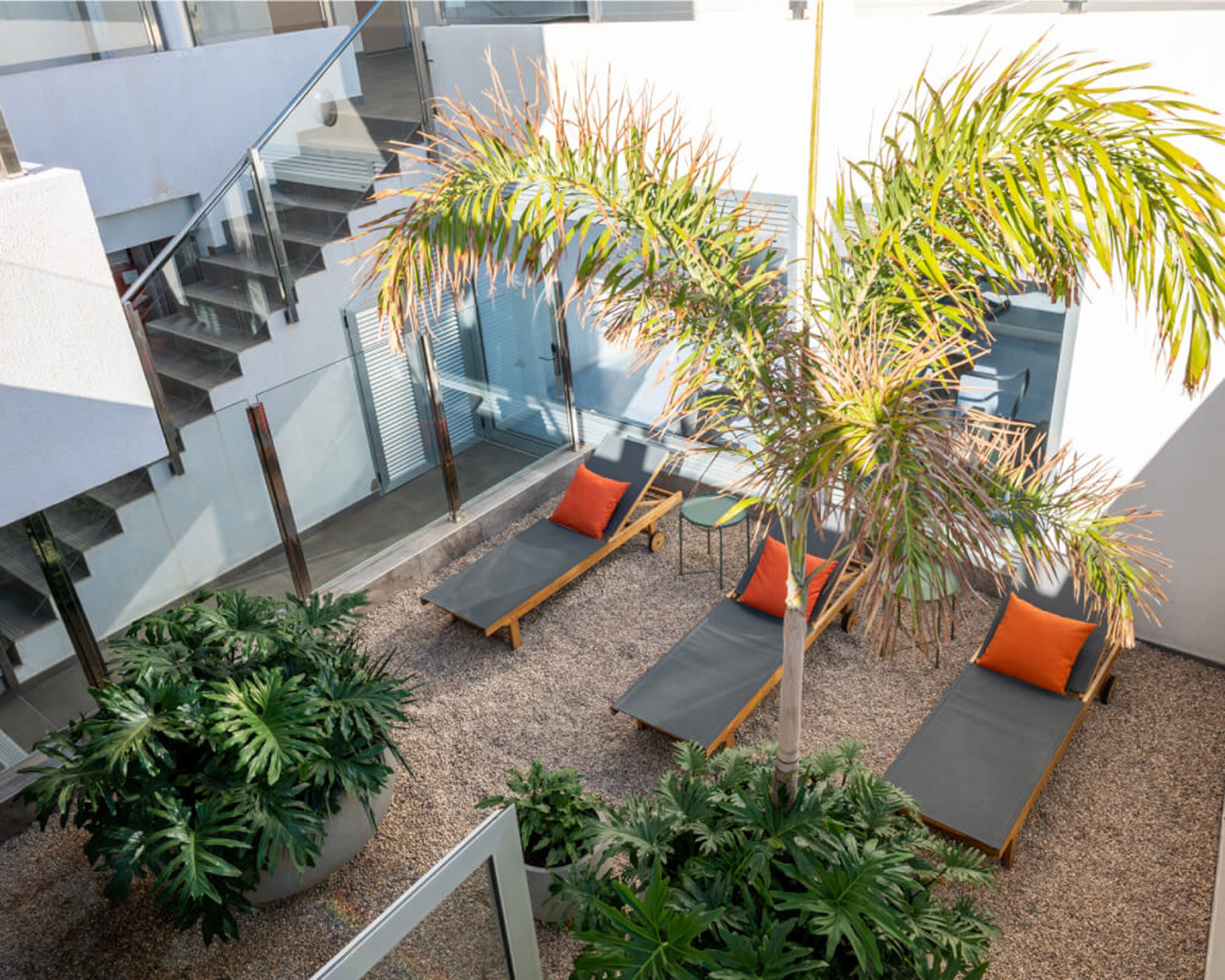 A rooftop lounge area with seating, a staircase, and potted plants.