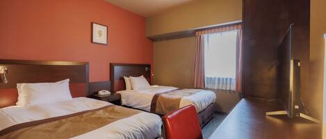 A hotel room with two beds, a desk, and a chair.
