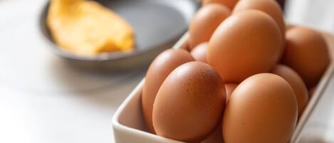 Un tazón de huevos y una sartén sobre una mesa.