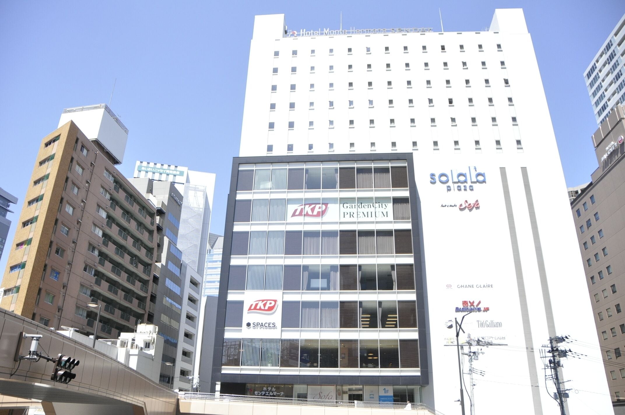 A multi-story building with 'TKP Premium' and 'Solala Plaza' signage, featuring a modern glass facade and multiple balconies.