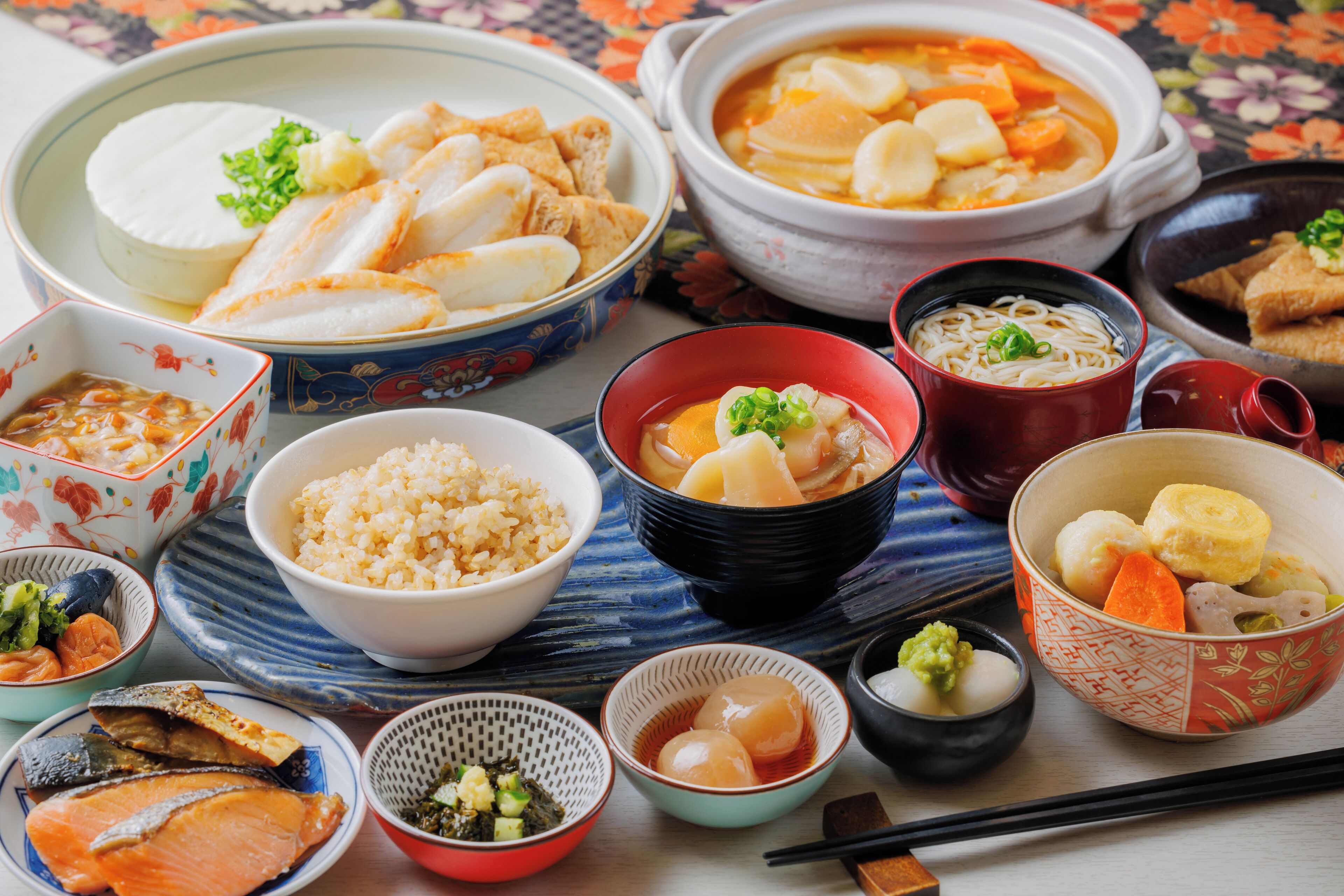 A variety of Japanese dishes including sushi, rice, and soup, arranged on a table with chopsticks and bowls.