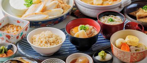 A variety of Japanese dishes including sushi, rice, and soup, arranged on a table with chopsticks and bowls.