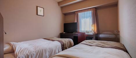 A hotel room with two beds, a desk, a television, and a window with curtains.