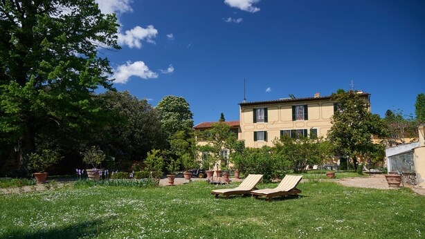 Une villa avec un jardin, deux chaises longues et un ciel d’un bleu éclatant.