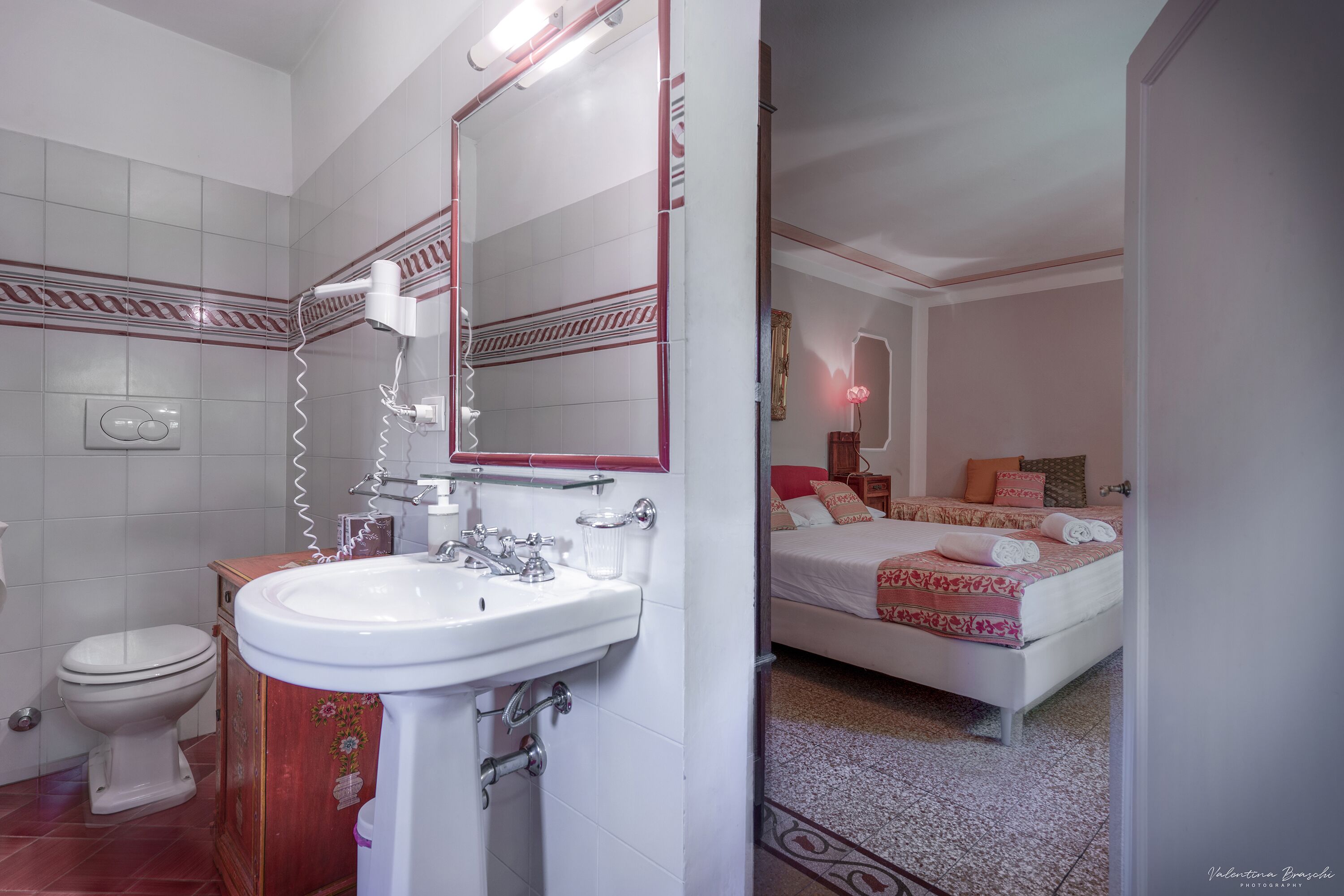 Un bagno con un lavandino bianco, un asciugacapelli e un water.