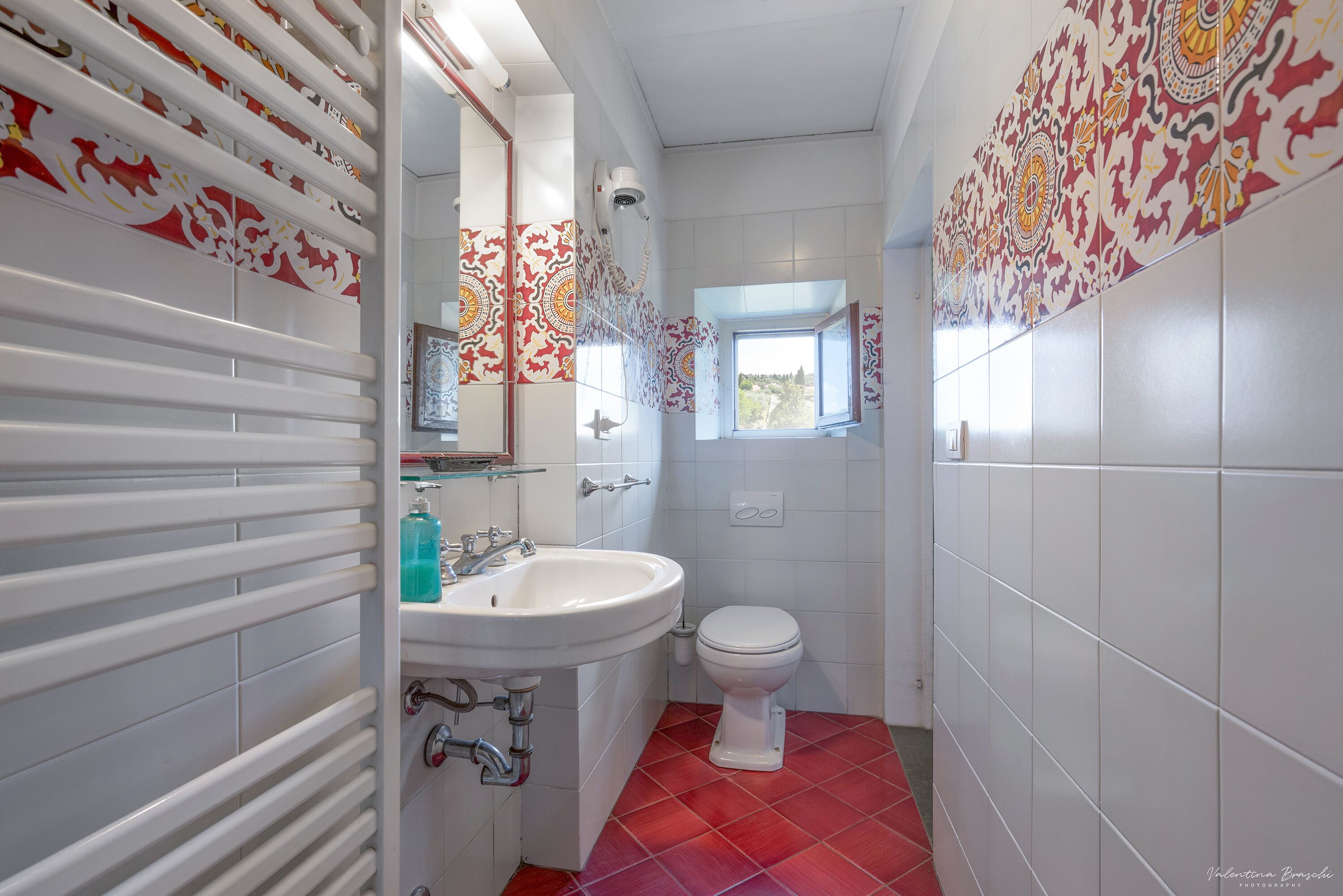 Un bagno con un lavandino bianco, il water e una finestra con vista.
