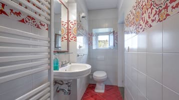 Un bagno con un lavandino bianco, il water e una finestra con vista.