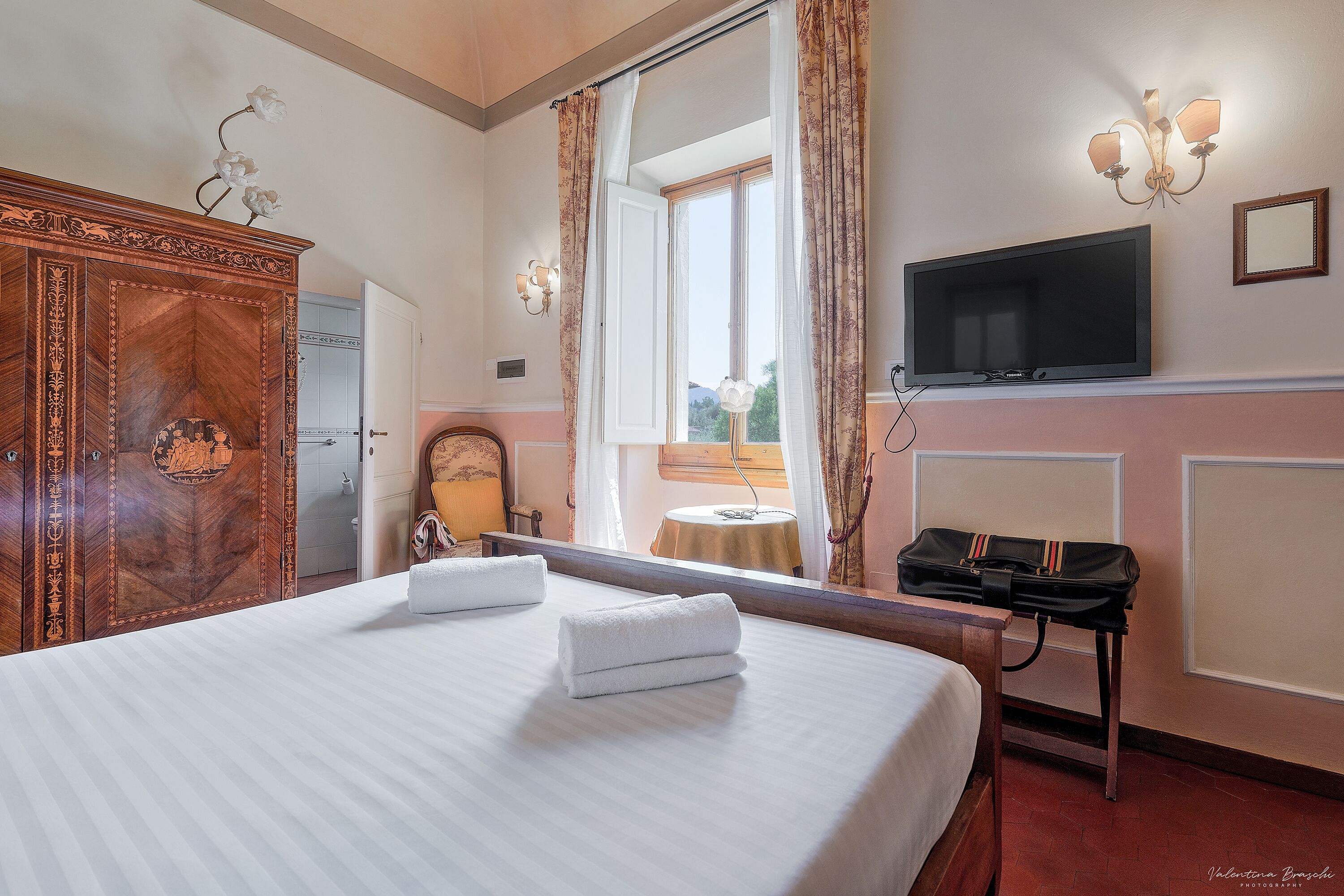 Una habitación de hotel con una cama grande, un armario, un televisor y un espejo.