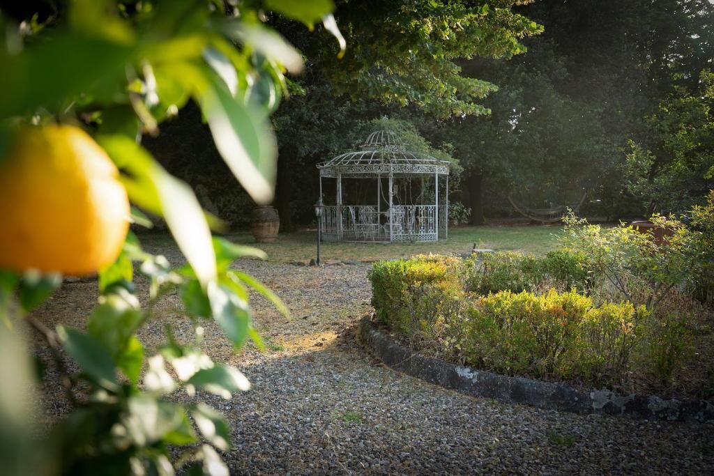 A gazebo in a garden with gravel paths and greenery.