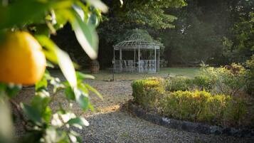 A gazebo in a garden with gravel paths and greenery.