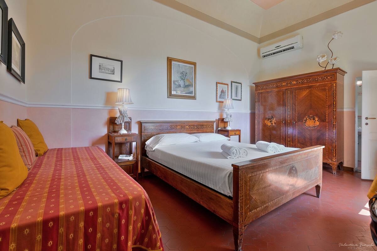A hotel room with a wooden bed, a wooden wardrobe, and a nightstand with a lamp.