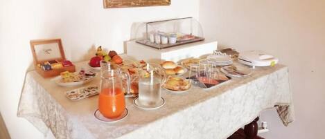 A breakfast buffet table with various food items and a juice pitcher.