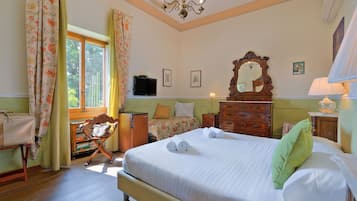 Une chambre à coucher avec un grand lit, une commode en bois, un bureau avec une chaise, une télévision et une fenêtre avec des rideaux.