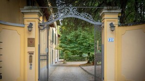 Une entrée fermée par un portail, avec une plaque portant le numéro 12, un portail en métal et un chemin menant à un bâtiment.