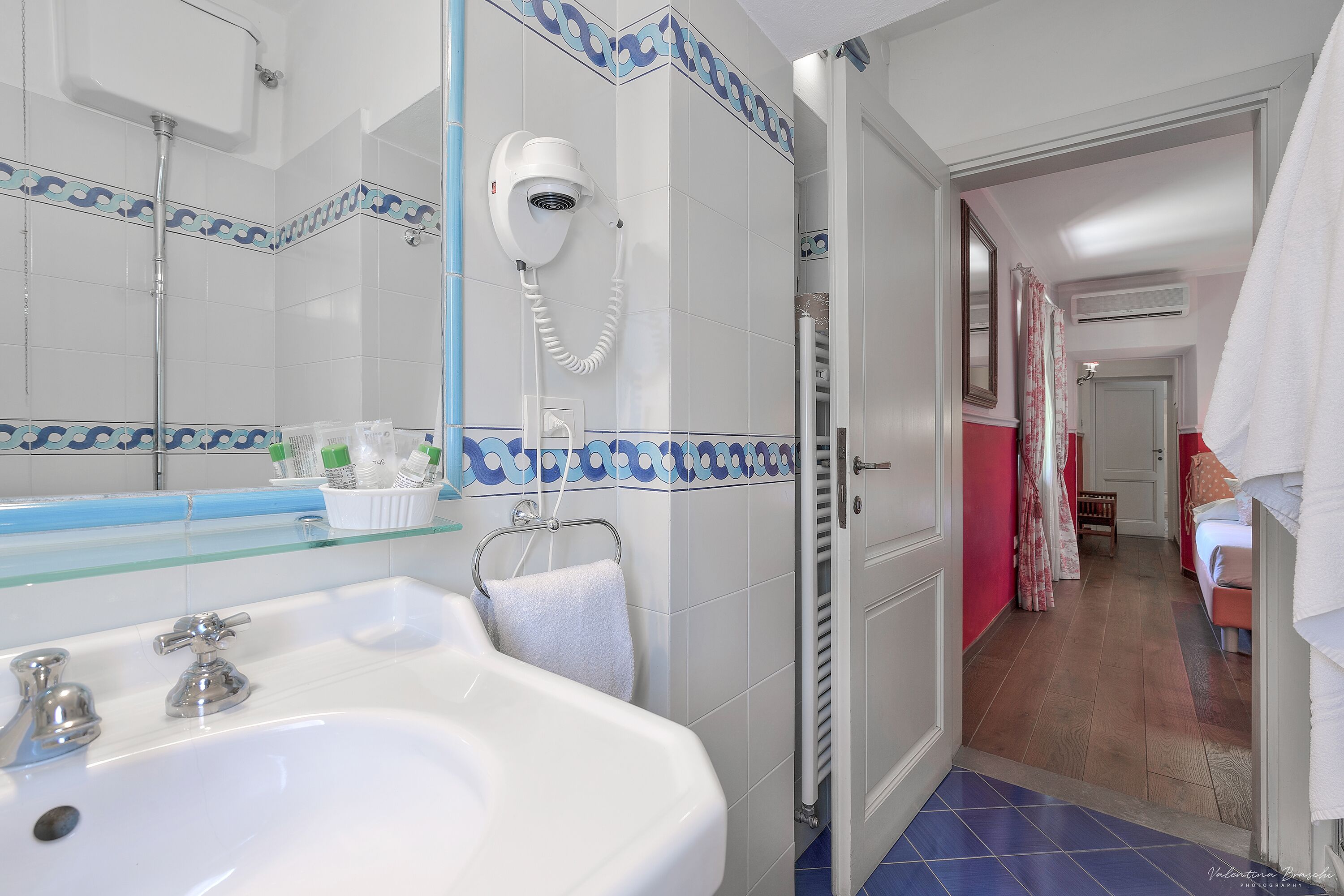 Une salle de bain avec un lavabo blanc, un sèche-cheveux et un porte-serviettes.