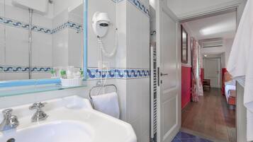 Une salle de bain avec un lavabo blanc, un sèche-cheveux et un porte-serviettes.