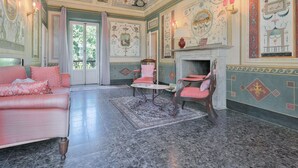 Une pièce dotée d’un sol en marbre, d’un canapé rose, d’une petite table ronde et de chaises avec des coussins roses.