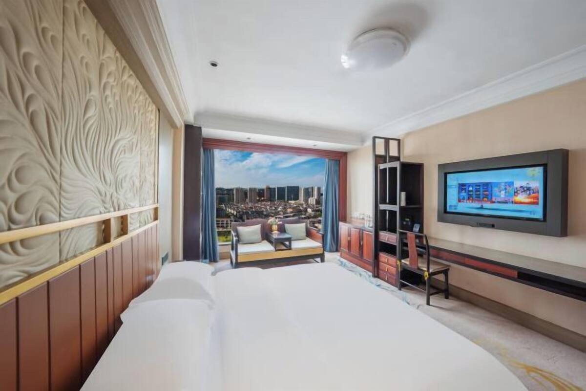 Hotelkamer met een groot bed, een televisie, een zithoek met uitzicht en een decoratieve wand.