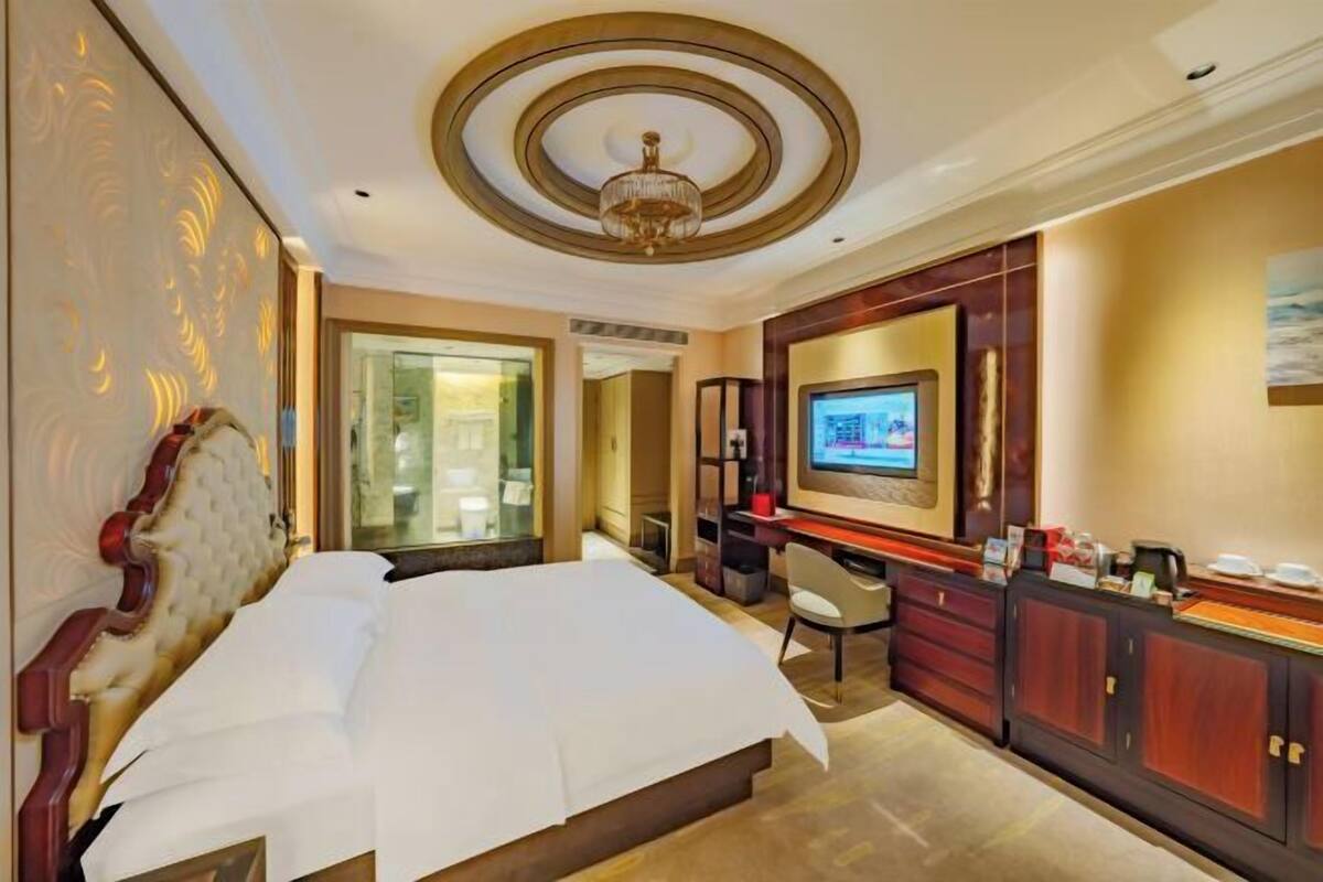 Een hotelkamer met een groot bed, een televisie, een bureau en een stoel.