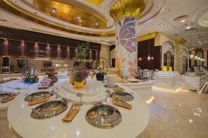 A luxurious hotel lobby with a central round table set for dining, a large decorative pillar, and a reception area with a counter and seating. - Haitian Hotel (Jinhua)