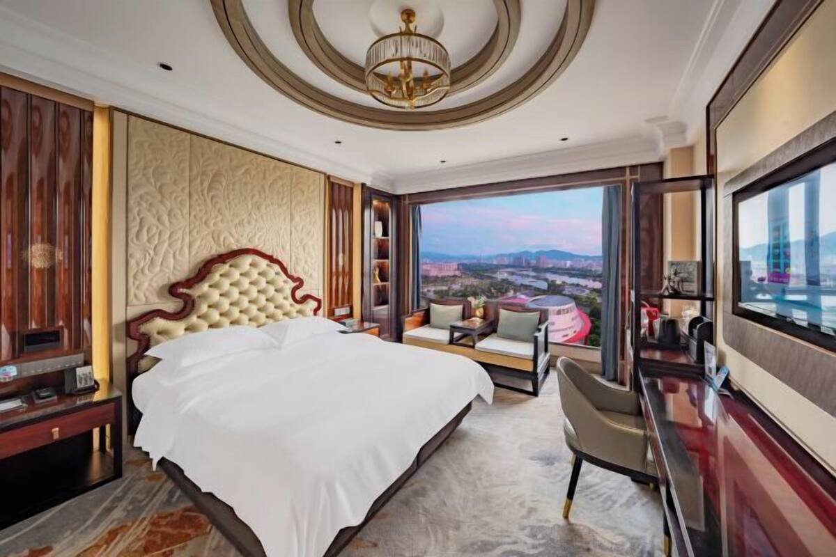 Hotelkamer met een groot bed, een bureau, een stoel, een televisietoestel en uitzicht op de stadsgezicht.