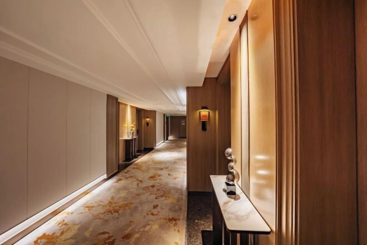A hotel corridor with a marble floor, wooden paneling, and a long reception desk with a decorative sculpture.