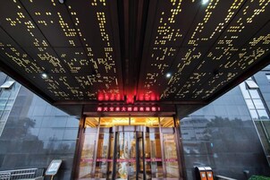 A building entrance with a digital display on the ceiling and a glass facade.