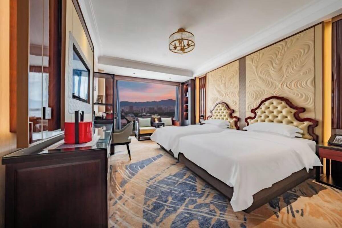 Een hotelkamer met een groot bed, een bureau, een stoel en uitzicht op de bergen.