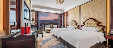 A hotel room with a large bed, a desk, a chair, and a view of the mountains.