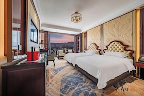A hotel room with a large bed, a desk, a chair, and a view of the mountains. - Haitian Hotel (Jinhua)