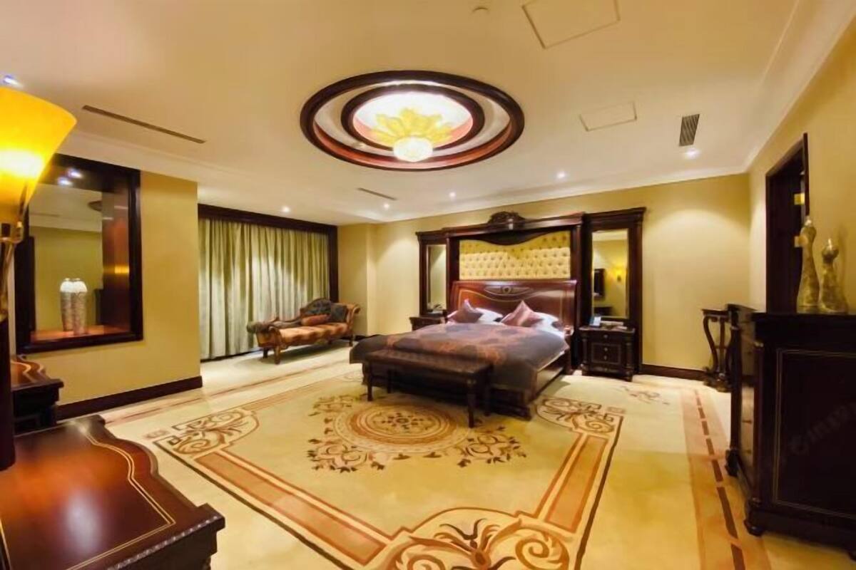 Een hotelkamer met een bed, een stoel, een bureau en een grote spiegel.