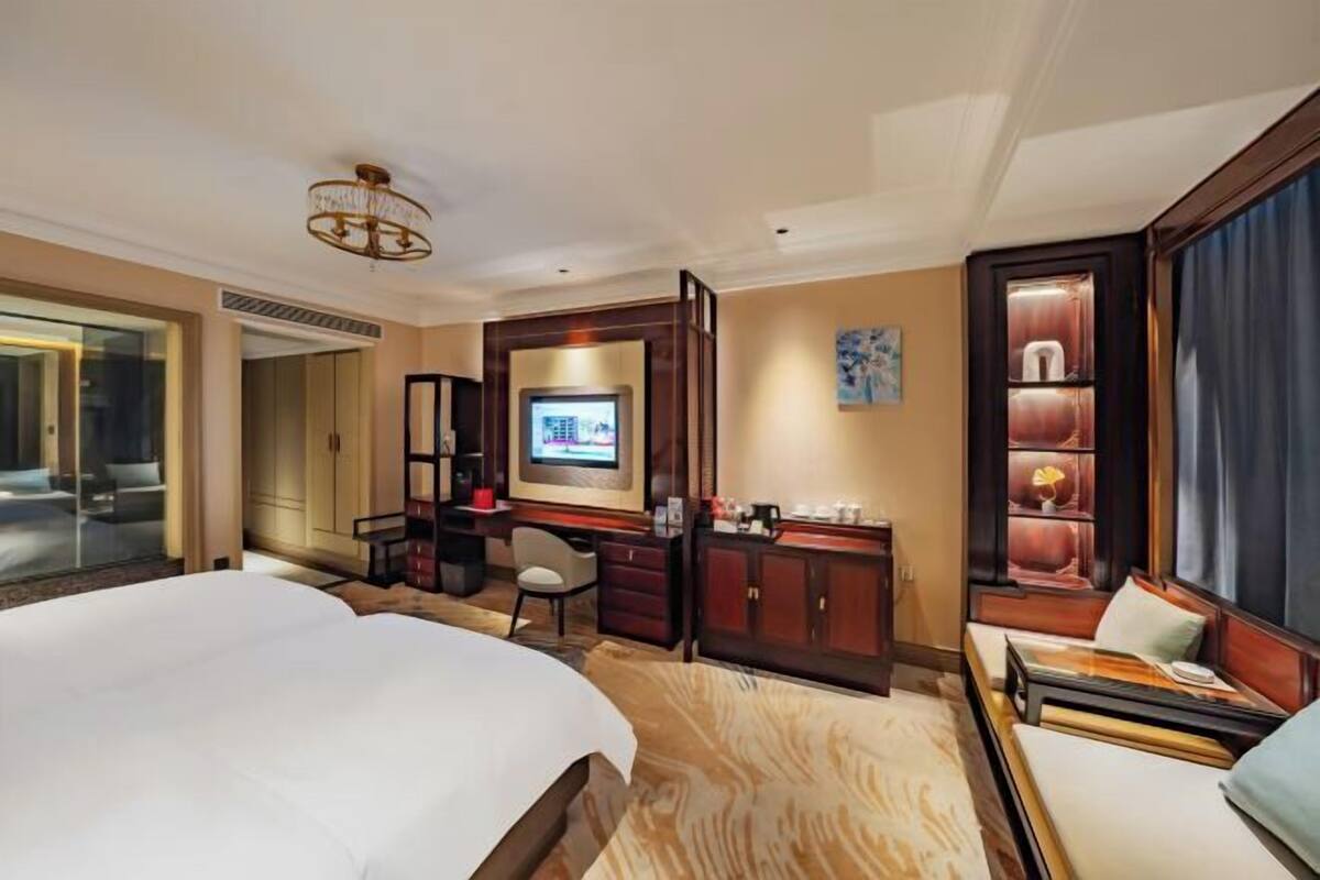 Hotelkamer met een groot bed, een bureau met computer, een televisie en een zithoek met uitzicht.