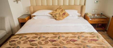 Una habitación de hotel con cama, mesita de noche, lámpara y teléfono.