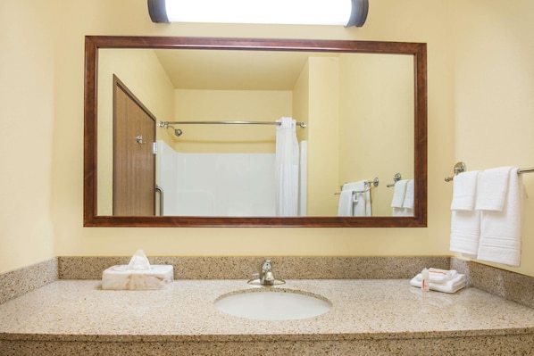 A bathroom with a sink, mirror, and towel rack. - Days Inn by Wyndham Ellis (Ellis)