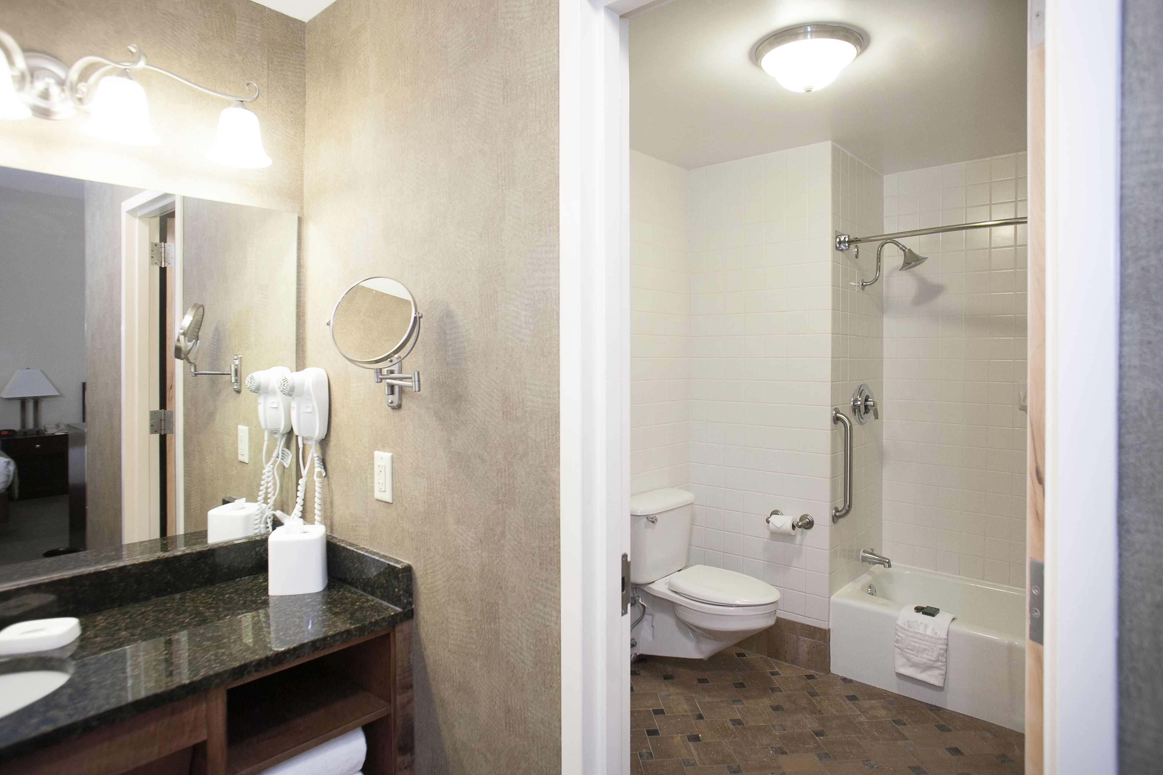 A bathroom with a sink, mirror, hairdryer, toilet, and bathtub.