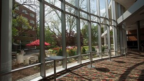 A spacious indoor area with large windows, a patterned carpet, and outdoor seating visible through the windows. - The University of Georgia Center for Continuing Education & Hotel (Athens)